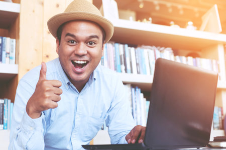 young man hand thumb up while using computer laptop happily.の写真素材