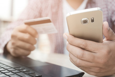 business man hands holding credit card and using phone and computer laptop. Online shopping purchase...