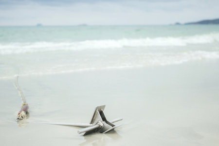An anchor from touristic boats on sandy beach with soft wave and sea form.の写真素材