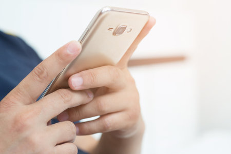 Close up hand young man cell phone addict man awake at morning using smartphone for chatting, flirting and sending text message in internet addiction and mobile Play all the time.の写真素材