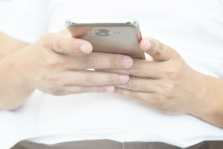 Close up hand young man cell phone addict man awake at morning using smartphone for chatting, flirting and sending text message in internet addiction and mobile Play all the time.の写真素材