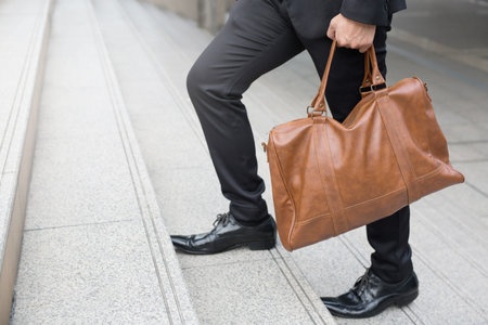 Businessman with briefcase brown leather bag walking upstairs ,Fighting against obstacles Climb up to Successful finish concept.の写真素材