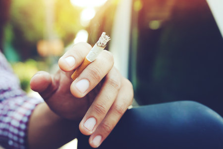 man plaid shirt stand smoking cigarettes in hand.の写真素材