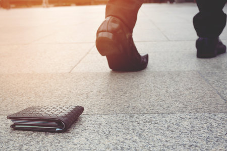 businessman had lost leather wallet with money on the street. Close-up of wallet lying on the...