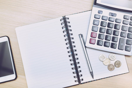 Money (coins), calculator and notebook,notepad,pen on wood table, top view with copy space - financial background conceptの写真素材