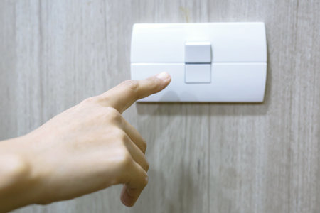 Turn off the light, close up female hand is closing the power switch. Save energy, reduce global warming.の写真素材