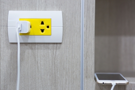 plugging adapter charge the battery with outlet socket plug and hold mobile phone on wall ,electric safety concept.の写真素材