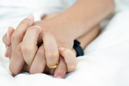 Hands stranglehold of couple lovers on a bed at honeymoon with lust and love. Concept about love, sex and lifestyle.の写真素材
