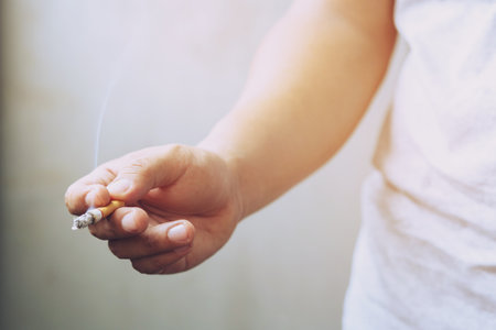 The man smoking a cigarette in hand. Cigarette smoke spread.の写真素材