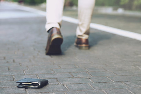 people young man had lost leather wallet with money on the street. Close-up of wallet lying on the...