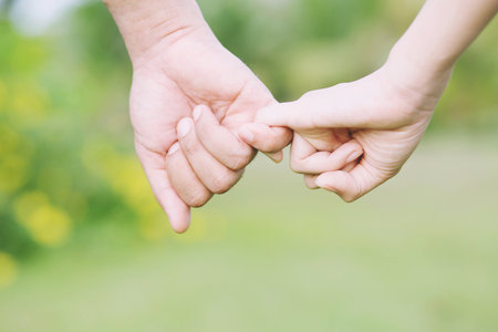Loving Young love Woman and man holding hand Shake hand together, couple be hand in hand pinky promise or pinky swear. Happy romantic love in the garden. concept couple lover valentine day.の写真素材