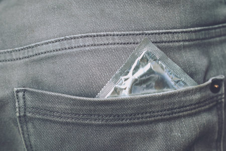 Young man jeans back side pocket to carry condoms taking in hand condom from jeans, safe sex concept on the bed Prevent infection.の写真素材