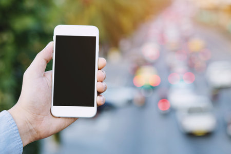 young people standing roadside sideways on footpath using mobile smart phone Call the car from the application rent a car. Technology transport travel concept.の写真素材