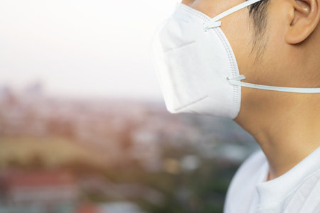 Portrait of man wearing facial hygienic mask nose outdoors. Ecology, air pollution car, Environmental and virus protection concept flu health against toxic dust covered the city of a health effect.の写真素材
