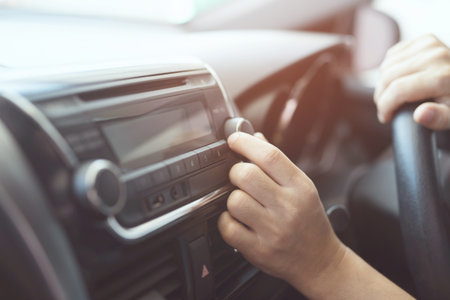 close up hand open car radio listening. Car Driver changing turning button Radio Stations on His Vehicle Multimedia System. Modern touch screen Audio stereo System. transportation and vehicle conceptの写真素材