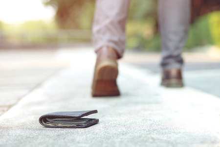 people young man had lost leather wallet with money on the street footpath sidewalk. Close-up of...