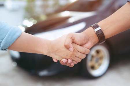 auto business. Close up of a business man dealer offer car to new owner and hand shake between two...
