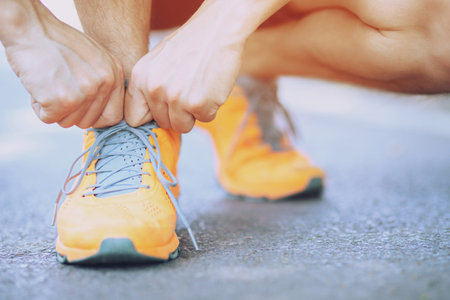 barefoot running shoes close up. male athlete tying laces shoelace for jogging on road concrete floor. Runner ties getting ready for training. Sport lifestyle.の写真素材