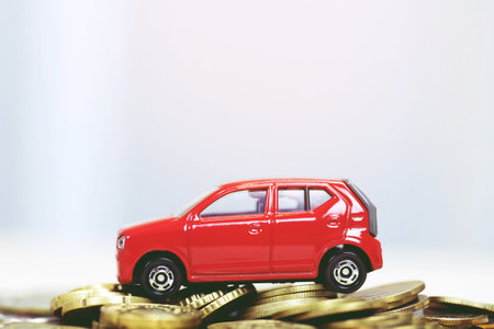 Little red car over a lot of money stacked coins. for bank loans costs finance. insurance, buying car finance concept. buy and pay by installments down payment a car.の写真素材