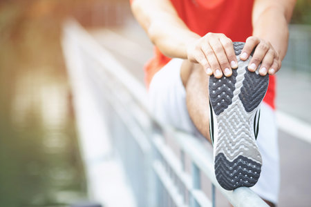 young man runner stretching for warming up before running or before a morning workout working out...