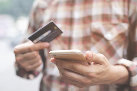 Online payment, Close up people man hands holding paying with credit card and using cell, smart phone for online shopping or reporting lost card, fraudulent transaction.の写真素材