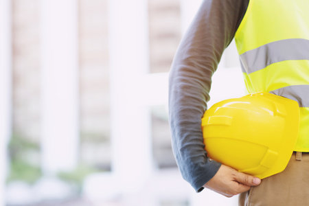 Close up backside view of engineering male construction worker stand holding safety yellow helmet...