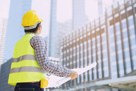 portrait of engineering asian man construction worker holding black folder Structural plan safety white helmet and wear reflective clothing for the safety of the work operation outdoor. soft focus.の写真素材