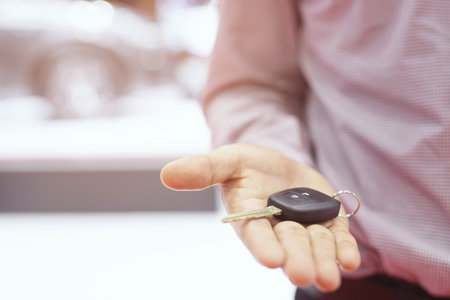 Car key, businessman handing over gives the car key to the other man on car background.の写真素材