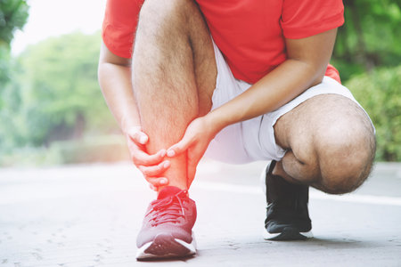 Runner touching painful twisted or broken ankle. Athlete runner training accident. Sport running ankle sprained sprain cause injury.の写真素材