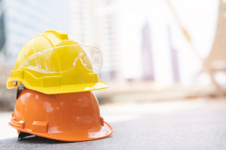 hard safety wear helmet hat in the project at construction site building on concrete floor on city with sunlight. helmet for workman as engineer or worker. concept safety first.の写真素材