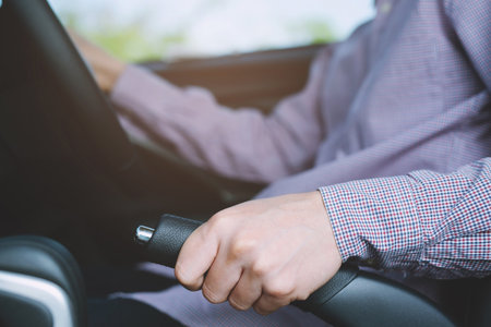 Closeup of person hand pulling handbrake lever in car For safety while parking.の写真素材
