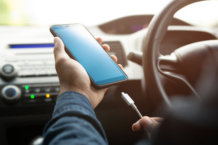 close up man hand holding charge the battery mobile smart phone in car. Leave the screen blank.の写真素材