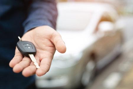 Car key, businessman handing over gives the car key to the other woman on car background.の写真素材