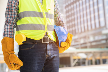 Close up front view of engineering male construction worker stand holding safety yellow helmet and...