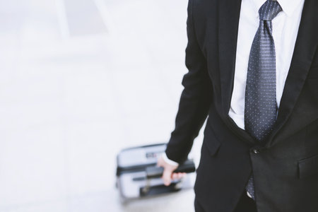 businessman walking outside public transport building with luggage in rush hour. Business traveler pulling suitcase in modern airport terminal. baggage business Trip. Copy space. soft focus.の写真素材
