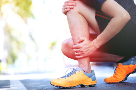 Runner touching painful twisted or broken ankle. Athlete runner training accident. Sport running ankle sprained sprain cause injury knee. and pain with leg bones. Focus red legs on to show pain.の写真素材
