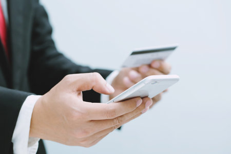 Close up young man hands holding paying with credit card and using cell, smart phone for online...
