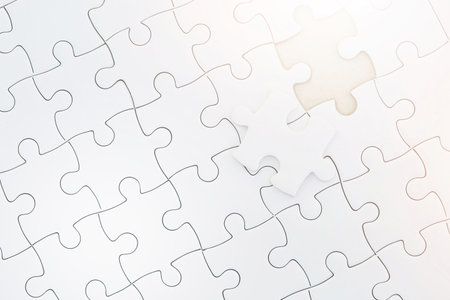 Close up Unfinished piece of white jigsaw puzzle. Complete the jigsaw puzzle with the missing pieces and Morning sunlight. concept of business challenge completion with teamwork.の写真素材