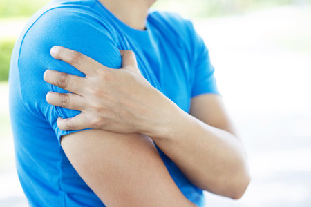 young man touching painful twisted or broken shoulder. Athlete training accident. Sport Exercise is...