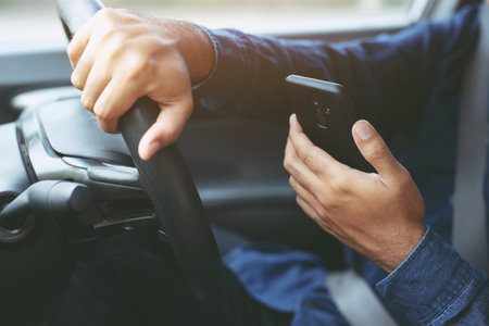 Young man driving using mobile smart phone while driving the car. transportation and vehicle conceptの写真素材