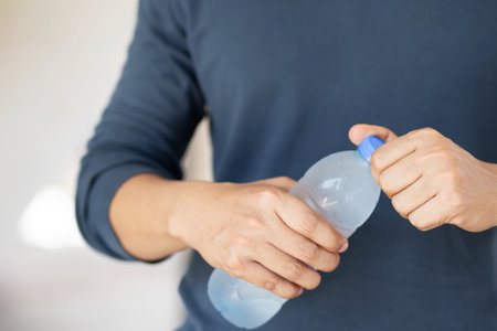 close up young man hand holding cool fresh drinking water bottle from a plastic. Open up, drink, quench thirst beverage For refreshing during the day.の写真素材