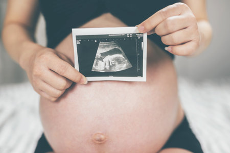 New mom Pregnant woman in white underwear Heart-shaped hand show love with baby. Young woman...