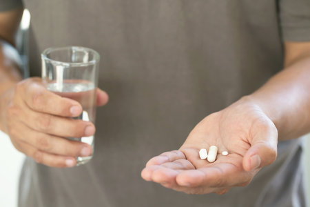 Close up man hand holding a medicine, with pours the pills out of the bottle.の写真素材