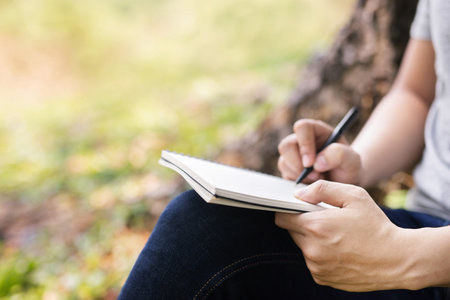 close up hand young man are sitting using pen writing Record Lecture notepad into the book in the...