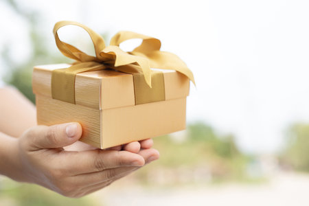 female hands holding open gift box dark black wrapped pack with beautiful red ribbon. for surprise...