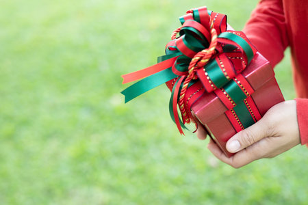 female hands holding open gift box dark black wrapped pack with beautiful red ribbon. for surprise...