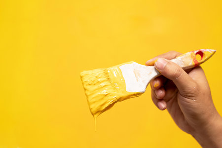 The mechanic is painting the yellow wall in the home studio room.