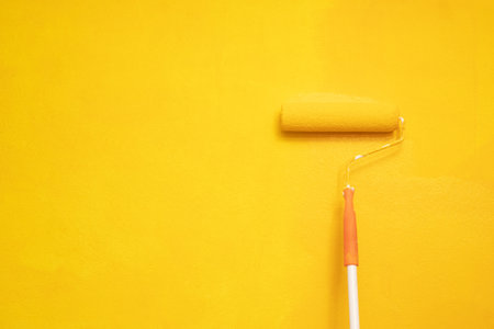 The mechanic is painting the yellow wall in the home studio room.