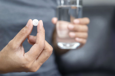 close up hand woman taking pill take a medicine in hand holding a cup glass of drinking water. Stop drug use Taking Medication health care medical concept.の写真素材