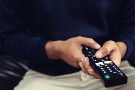 A man is watching a live broadcast on TV at home.